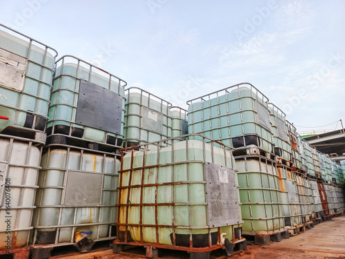 IBC totes industrial plastic containers stacked and stored outdoors under open sky logistic distribution supply chain equipment storage in manufacturing production yard