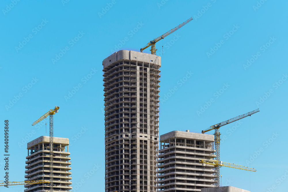 Fototapeta premium Construction of tall multistorey residential tower in developing metropolitan district. Unfinished