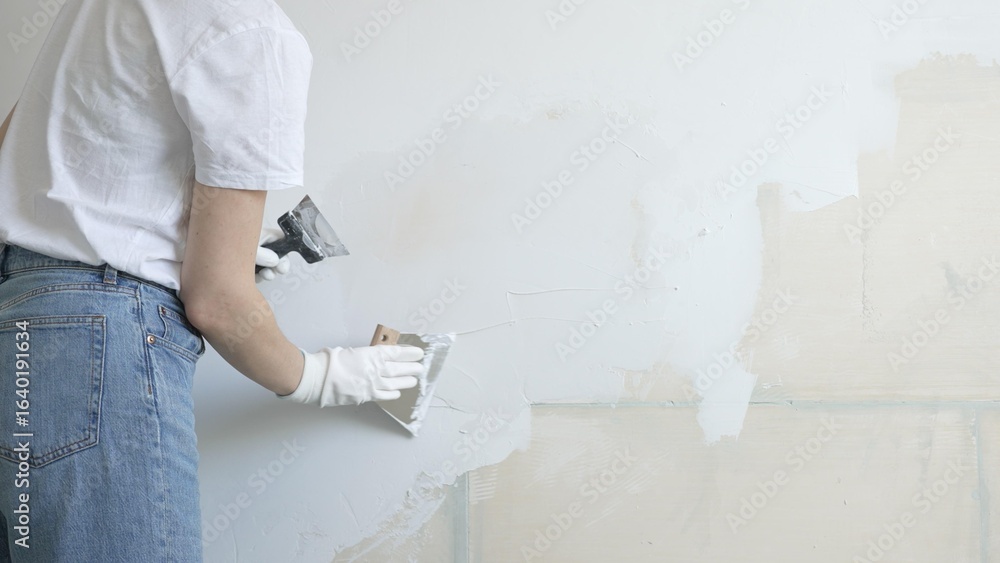 Fotografie Unknown female construction worker applying plaster with putty knife, smoothing