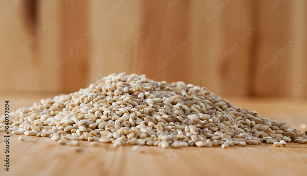 Obraz premium Pearl barley on a wooden surface, macro