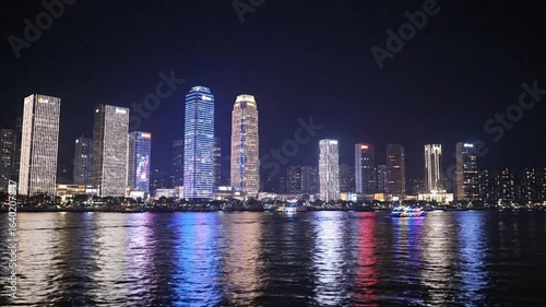 Wallpaper Mural Night cityscape with illuminated skyscrapers reflected in rippling water A colorful boat is visible Torontodigital.ca