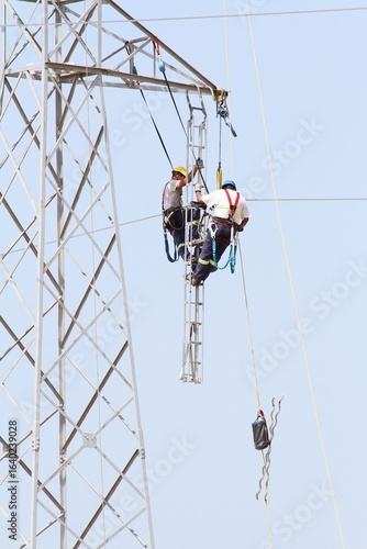 High-voltage tower repair technicians working suspended 20 meters above the ground.