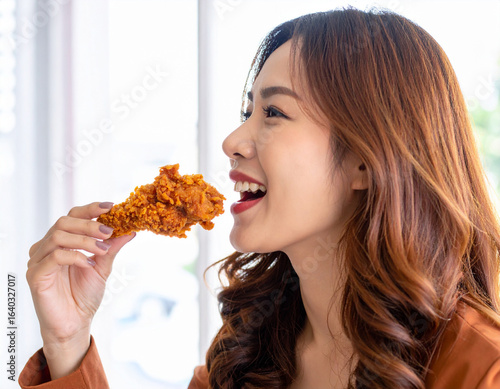 フライドチキンを食べる若い女性/
Young woman eating fried chicken