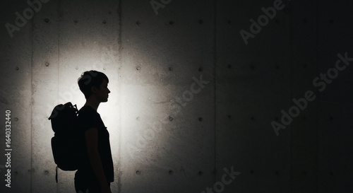 Wallpaper Mural Dramatic Silhouette of Traveler with Backpack Against Spotlighted Concrete Wall. Torontodigital.ca