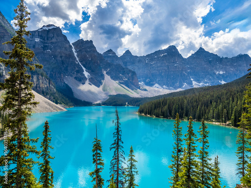 Turquoise Moraine Lake with pine forest and rugged mountain peaks
