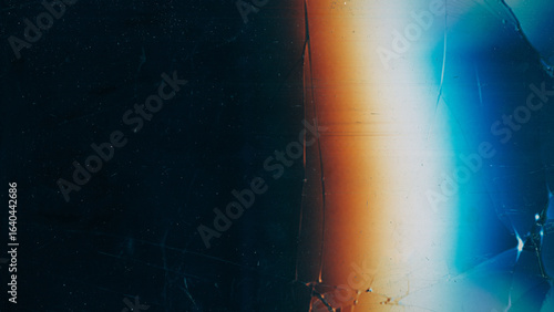 Scratched black glass. Damaged texture. Vintage dust cracked dark screen. Colorful light blur glow abstract night background free space.