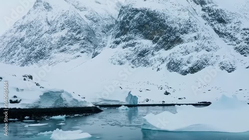 Arctic Majesty: Iceberg at the Base of Snow-Covered Mountains