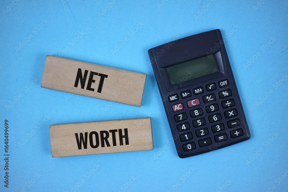 Wooden Blocks with 'Net Worth' Text Beside a Calculator on blue Background Wooden Blocks with 'Net Worth' Text Beside a Calculator on blue Background