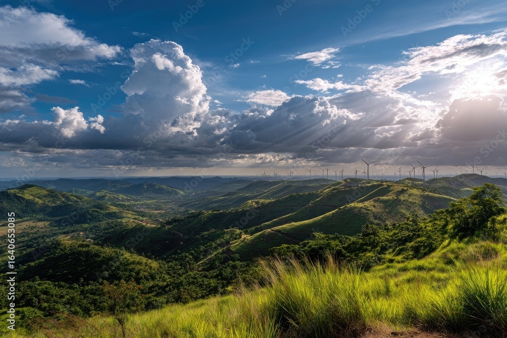 Naklejka premium Panoramic vista of rolling hills, lush greenery, wind turbines, and dramatic clouds