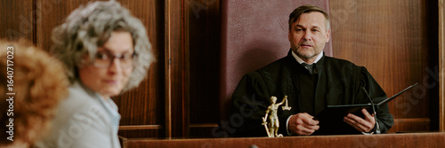Tableau sur toile Caucasian middle aged man judge holding folder presiding over courtroom session