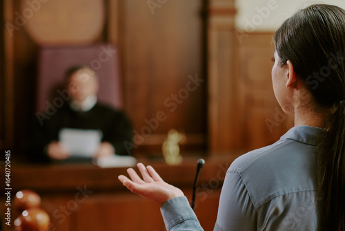 Tableau sur toile Young adult Asian woman testifying in courtroom, standing in front of judge, ges