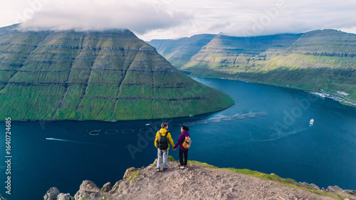 Slika na platnu Breathtaking view of hikers overlooking the stunning landscape of Faroe Islands