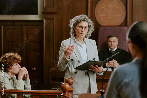 Photography Caucasian middle aged woman lawyer addressing courtroom while holding folder, Ca