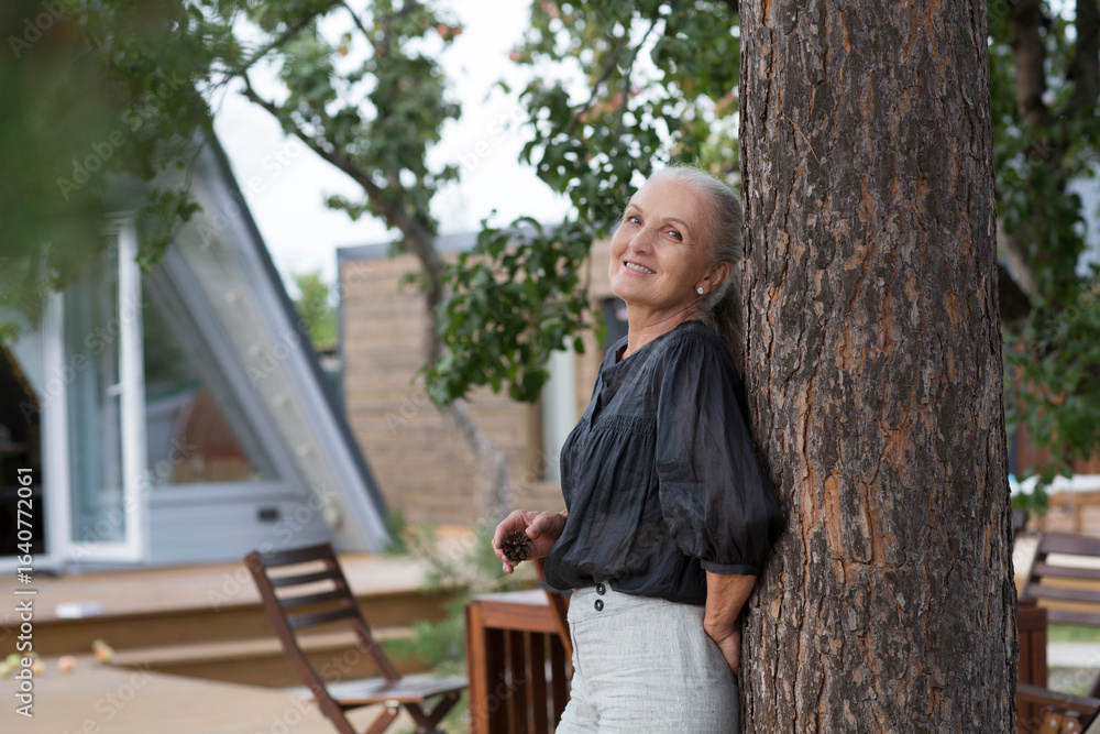 Fototapeta premium portrait of a cheerful elderly woman in the garden about her home. Enjoying the little things. spends time in nature in summer