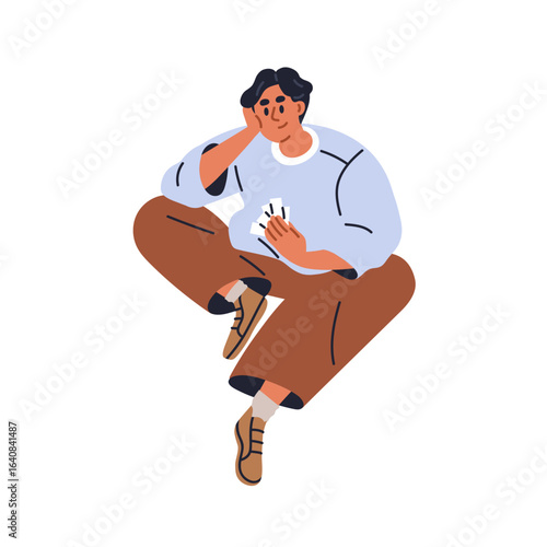 Man sitting, holding paper cards. Young male in thoughtful pose. Person leani...