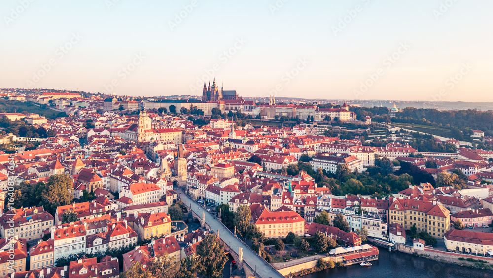Fototapeta premium A breathtaking view of Prague at sunrise reveals the city's iconic skyline. The Vltava river gracefully flows alongside historic buildings, with the Charles Bridge and castle in the background.