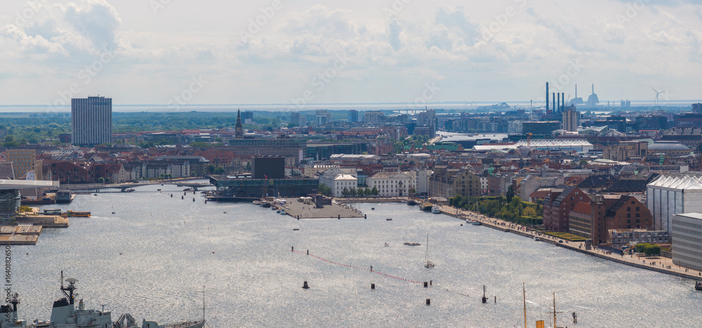 Fototapeta premium Aerial view of Copenhagen, Denmark, featuring the harbor, Amager Bakke waste to energy plant, Opera House, wind turbines, and a mix of urban architecture.