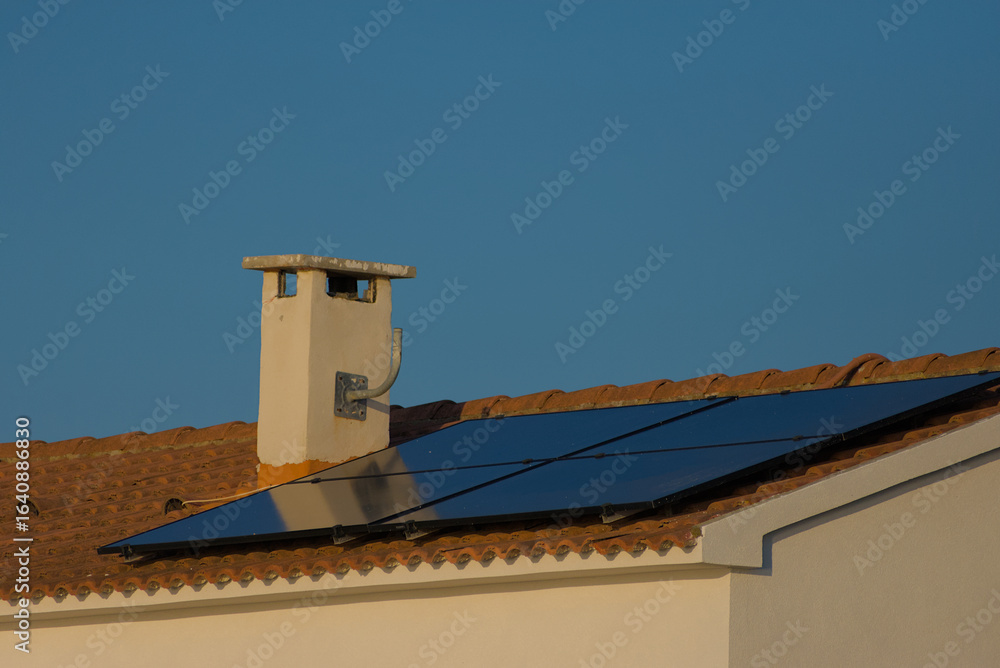 custom made wallpaper toronto digitalA rooftop solar panel system is installed on a house with a tiled roof and a chimney, set against a clear blue sky on a sunny day.