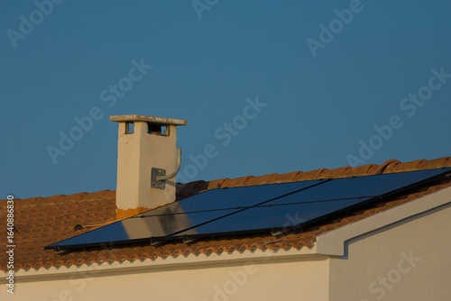 Wallpaper Mural A rooftop solar panel system is installed on a house with a tiled roof and a chimney, set against a clear blue sky on a sunny day. Torontodigital.ca