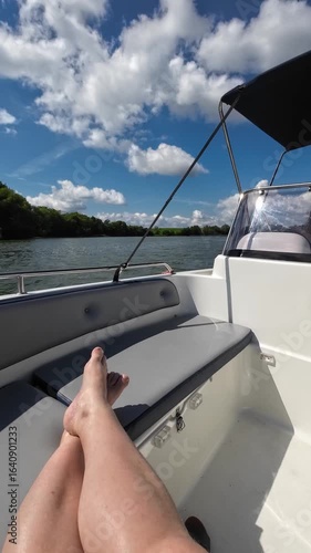 Wallpaper Mural A woman's legs are seen on a seat of a motorboat on a sunny day. The boat moves across a lake, with part of the driver's area visible. Summer vibe, water travel, and relaxation. Torontodigital.ca