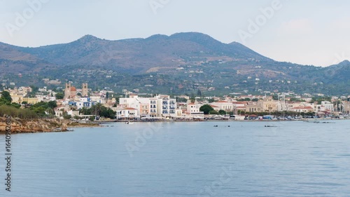 Wallpaper Mural Peaceful coastal town on Aegina Island, Greece, at the foot of hills, with calm bay waters, small boats, colorful Mediterranean houses, historic church, and bright sky Torontodigital.ca