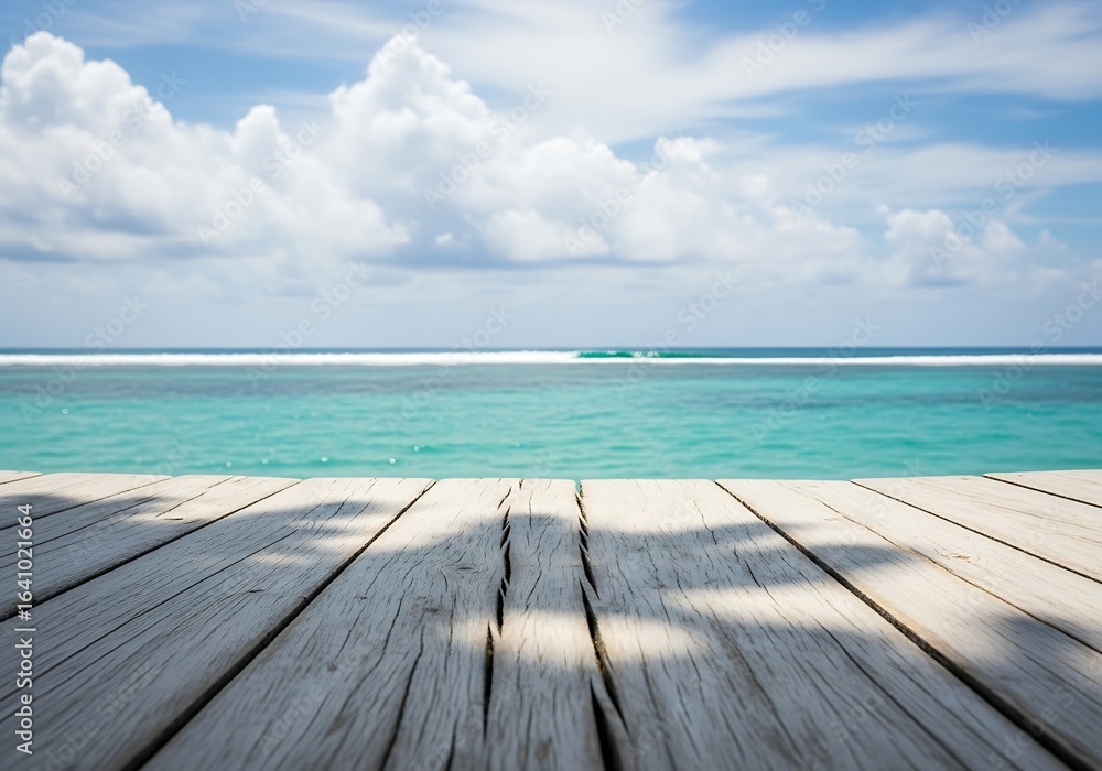 Fototapeta premium Wooden deck overlooking a serene turquoise ocean with white clouds in a bright blue sky, perfect for a tropical vacation getaway