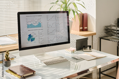 No people shot of modern computer monitor with graphs on screen on desk in office interior, copy space