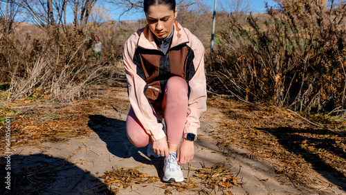Woman tying shoelaces before a run in a natural setting
