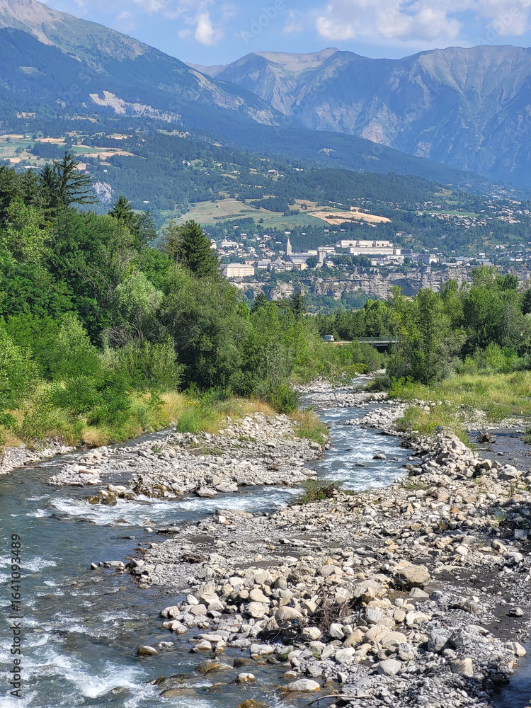 Fototapeta premium Torrent Vachères à Baratier avec la ville d'Embrun à l'horizon, Hautes-Alpes, France