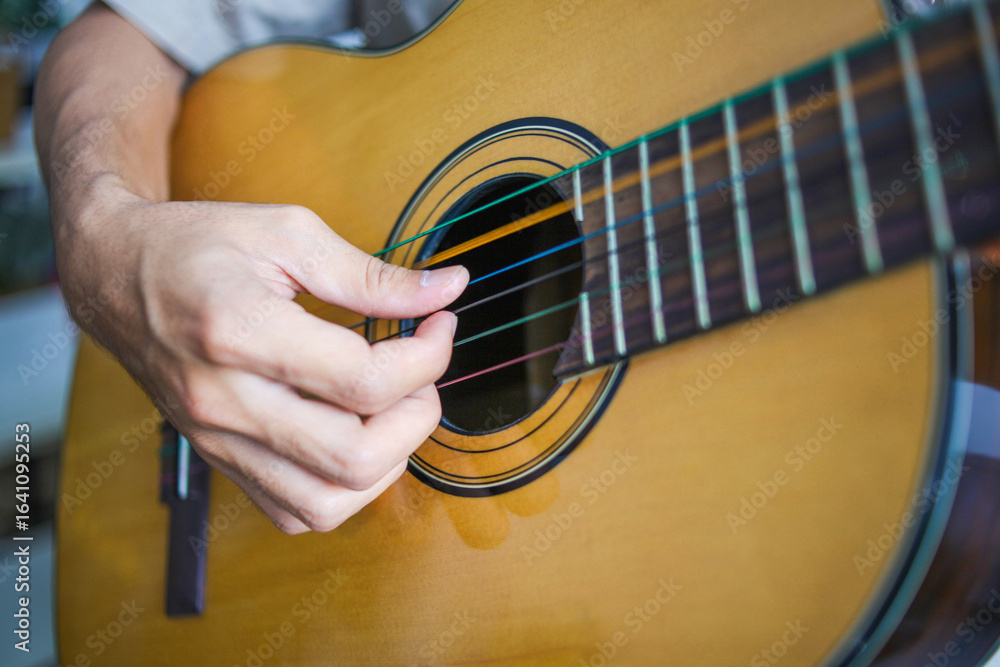 Fototapeta premium Close Up Of Musician's Fingers strumming The Strings Of Guitar