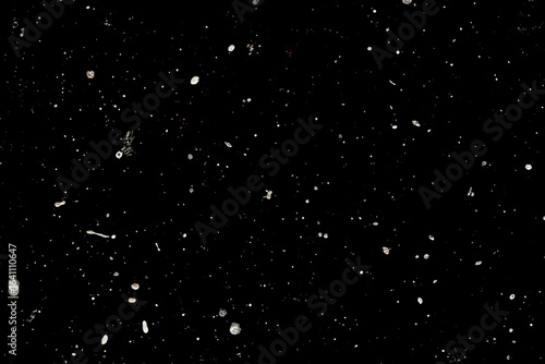 Abstract cosmic background with specks resembling stars and galaxies.