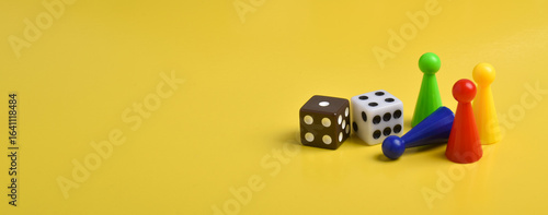 Colorful game chips and two dice isolated on a yellow background, banner, space for text
