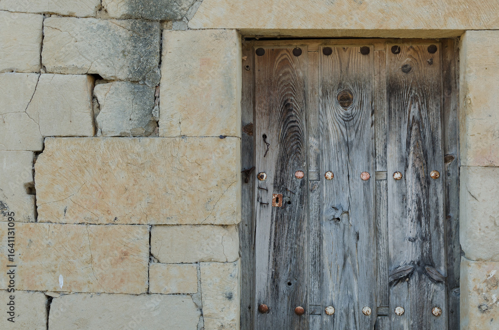 Front view of antique wooden damaged broken door with brown wood texture and metallic rusty vintage handle and keyhole and bolts from a spain village. Horizontal photo background with copy space Front view of antique wooden damaged broken door with brown wood texture and metallic rusty vintage handle and keyhole and bolts from a spain village. Horizontal photo background with copy space