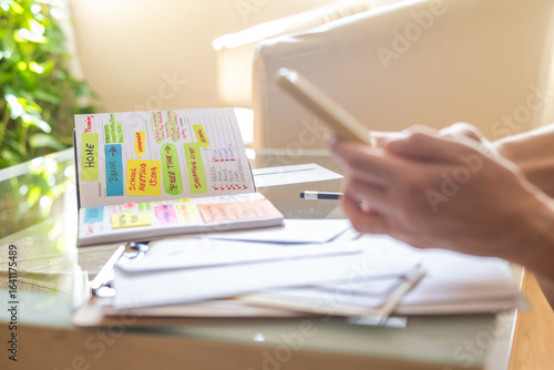Foto Woman is using smartphone and personal agenda to organize work, school meetings,