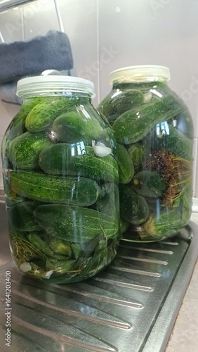 jars of pickled cucumbers, glass jars of pickled cucumbers in brine on kitchen sink