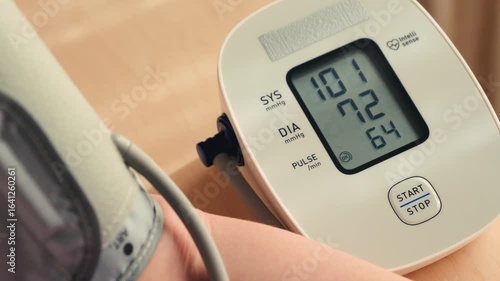 Female hand using automatic tonometer for blood pressure checking. High quality 4k footage