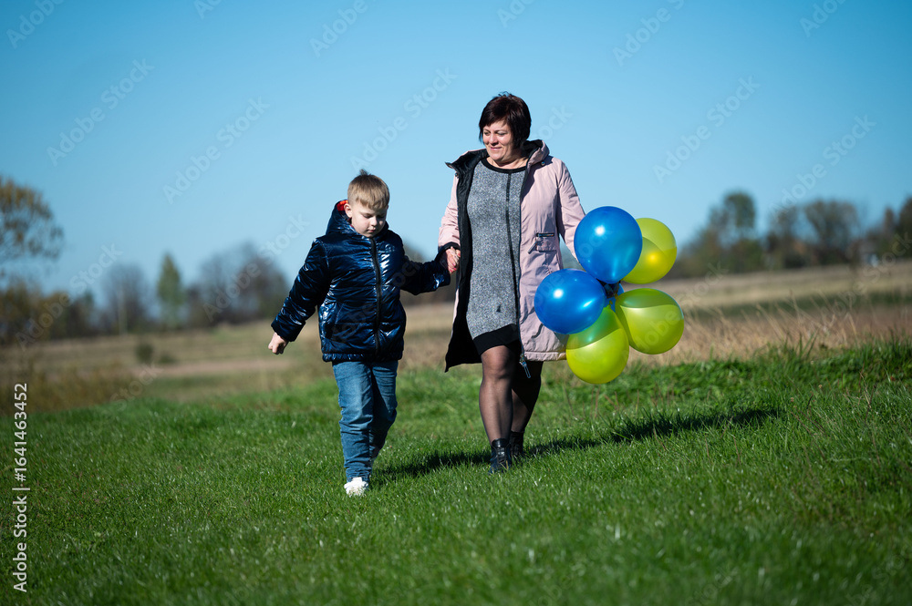 Joyful moments shared between mother and son on a sunny day in the park with colorful balloons highlighting their playful bond Joyful moments shared between mother and son on a sunny day in the park with colorful balloons highlighting their playful bond