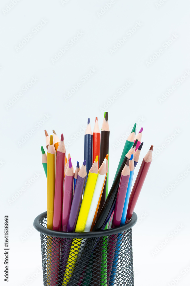 Fototapeta premium Colorful pencils standing in a black metal pencil holder on a white background