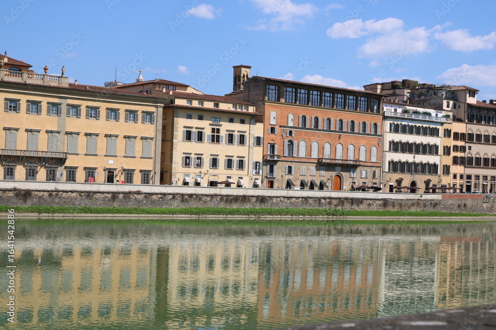 Fototapeta premium Houses buildings on the banks of river Arno. Buildings with reflections in the water, Firenze, Tuscany, Italy.
