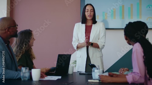 Confident businesswoman giving presentation to diverse team in boardroom of office during daytime