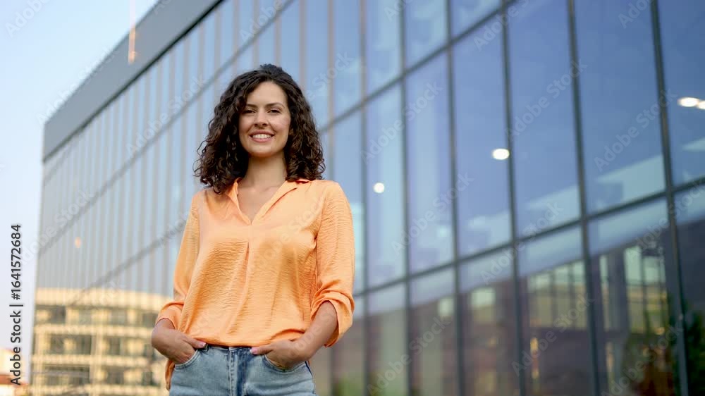 Confident businesswoman posing near sleek glass skyscraper, embodying corporate professional success in contemporary urban setting Confident businesswoman posing near sleek glass skyscraper, embodying corporate professional success in contemporary urban setting