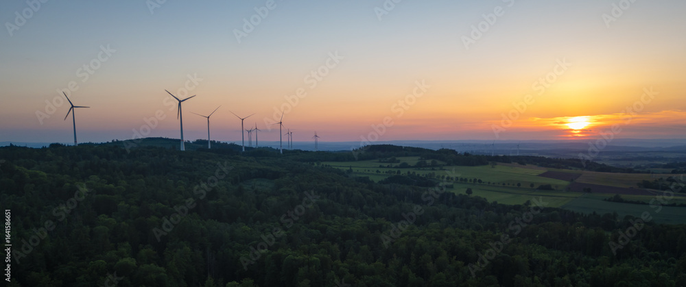 Obraz premium Last rays of light over the wind-turbine-dotted mountains and forest