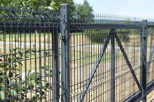 Black steel mesh fence with double entrance gate at residential property.