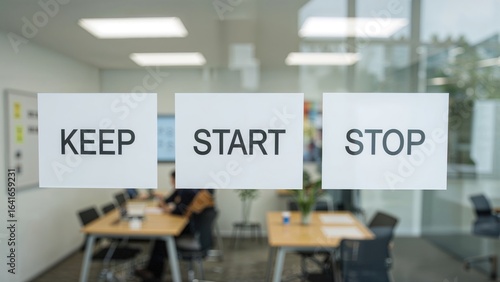 Three colorful Spanish labels reading keep, start, and stop are stuck on a window for a group working on a retrospective board with KISS and SCRUM techniques on an agile board.