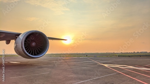 Close-up of commercial aircraft engine at airport apron during golden sunset, highlighting aviation technology and travel atmosphere