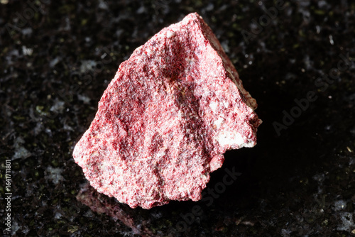sample of raw cinnabar mineral on black granite