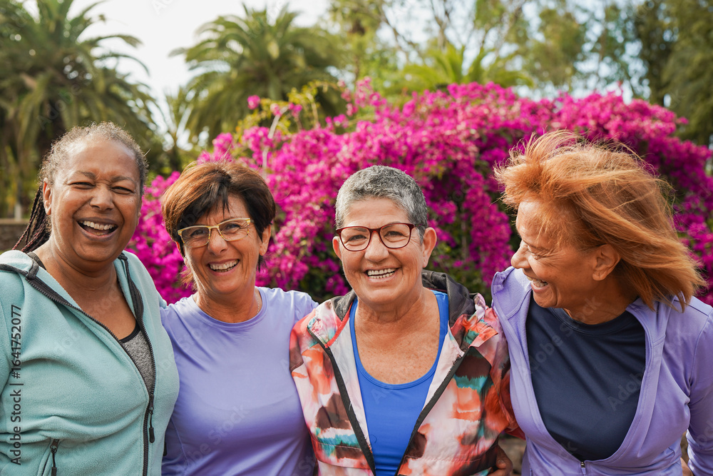 Obraz premium Happy multiracial senior women having fun together outdoor - Elderly generation people hugging each other at city park