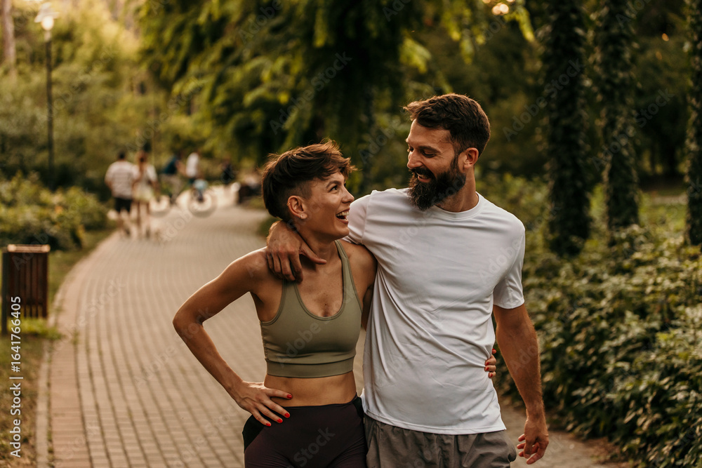 Obraz premium Happy couple walking and talking in park after exercising