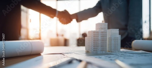 The handshake over architectural model symbolizes successful business collaboration and planning.