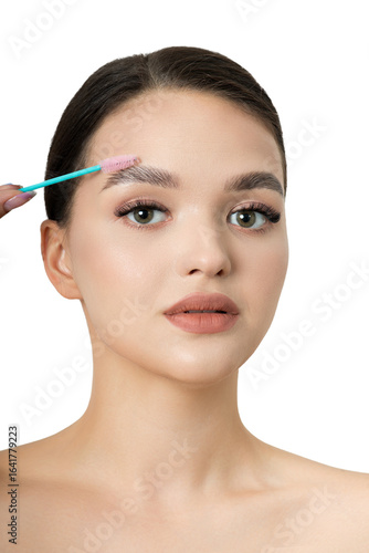 Young beautiful brunette girl with natural makeup and laminated brows holds brush for eyebrow corrections. Eyebrow correction and perm lamination procedure.
